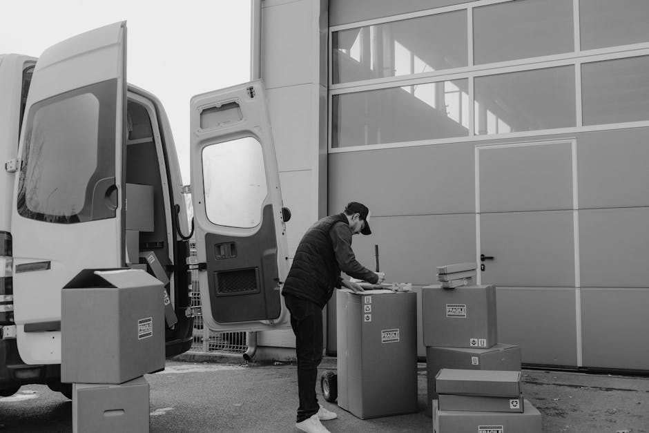 Inside a moving van loaded with neatly stacked cardboard boxes of various sizes, some with printed handling and recycling symbols, and one with a 'Fragile Handle With Care' label. The boxes are packed